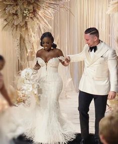 a bride and groom walking down the aisle at their wedding ceremony in white tuxedos