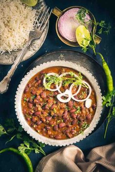 a bowl filled with beans and onions on top of a table next to other foods