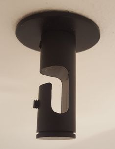 a black light fixture hanging from the ceiling in a room with white walls and flooring