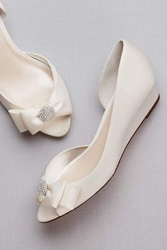 the bride's shoes are all white and have bows at the toe, which is adorned with crystal - embellishments