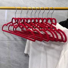 several red clothes hangers in front of a white shirt hanging on a yellow rail