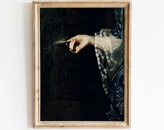 a painting hanging on the wall with a woman's hand holding something