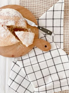 a wooden cutting board topped with a piece of cake next to a knife and napkin