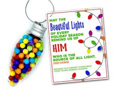 a christmas ornament with candy in it next to a tag that says, may the beautiful lights of every holiday season remind us of him