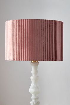 a white table lamp with a pink shade on it