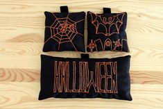 three black and orange halloween pillows sitting on top of a wooden floor