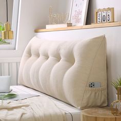 a close up of a bed with a pillow on it's side and a laptop