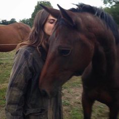 a woman standing next to a brown horse