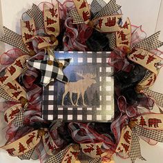 a christmas wreath with moose on it and red, white, and black ribbon around the edges