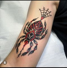 a spider web tattoo on the arm with red and black colors, it looks like an insect