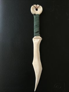 a white and green object hanging on a black wall in the shape of a knife