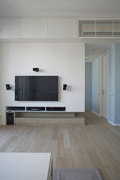 a flat screen tv mounted to the side of a wall in an empty living room