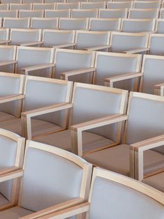 rows of white chairs with wooden frames in an auditorium