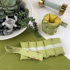 a table topped with green napkins next to a bowl filled with succulents