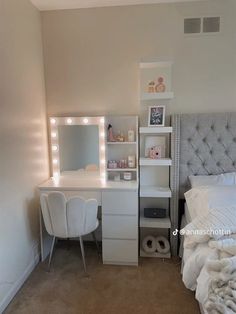 a bedroom with a bed, desk and lighted vanity mirror in the corner next to it