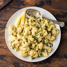 cauliflower and lemon on a white plate with a serving spoon next to it