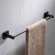 a towel hanging on the side of a wall next to a toilet paper roll and a towel rack