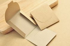 an open cardboard box sitting on top of a wooden table next to a piece of paper