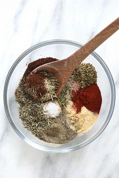 spices and seasonings in a glass bowl with a wooden spoon