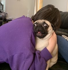 a woman is hugging her pug on the couch