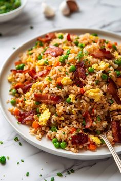 a white plate topped with fried rice and veggies next to a bowl of peas