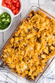 a casserole dish with tortilla shells and vegetables in the bowl next to it