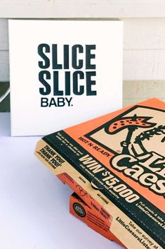 a close up of a box on a table with a sign in the background that says slice slice baby