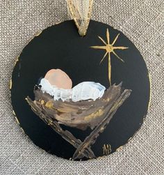 a black ornament with a painting of a baby jesus in a manger