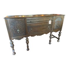 an antique wooden sideboard with ornate carvings on the doors and drawers, is shown against a white background