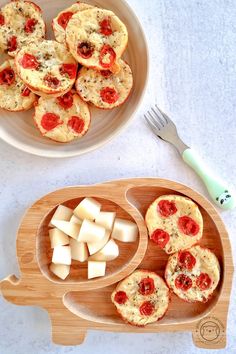 some food is sitting on a wooden tray and next to a plate with mini muffins