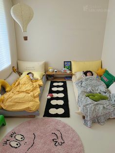 two children sleeping on their beds in a room with rugs and pillows around them