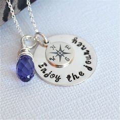 a silver necklace with a compass charm and a blue crystal bead hanging from it