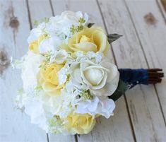 a bridal bouquet with yellow and white flowers on a wooden table, ready to be used as a bride's bouquet