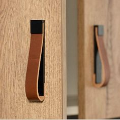 a close up of a door handle on a wooden cabinet with a leather strap around it