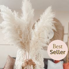 a person holding up some white feathers in their hands and the words best seller above them