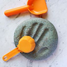 two orange plastic scoops sitting on top of a stone