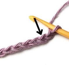 the crochet hook is being used to make a knitted stitch with an arrow