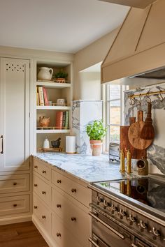 a kitchen with white cabinets and marble counter tops, along with an oven hood over the stove