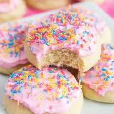 two donuts with pink frosting and sprinkles are in a box