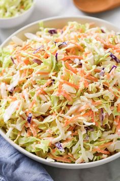 a bowl filled with coleslaw and carrots on top of a white table