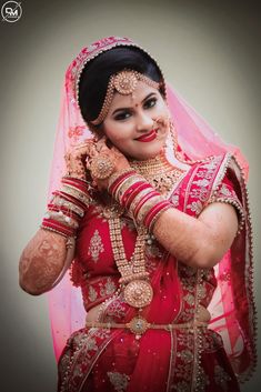 a woman in a red and gold bridal outfit with her hands on her face