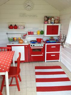 a red and white kitchen with an oven, stove, table and chairs in it