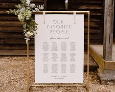 a wedding seating sign with flowers on it in front of a wooden structure and building