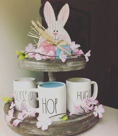 two coffee mugs sitting on top of a wooden tray with bunny ears and flowers