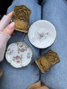 a person is sitting down with four small plates and two teacups on their legs