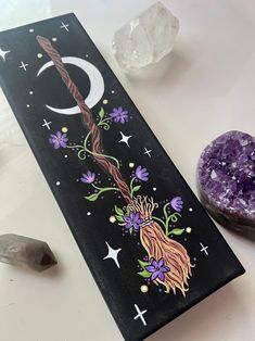 a painting on a table next to crystals and a rock with the moon painted on it