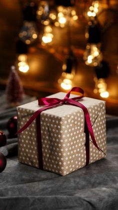 a present wrapped in brown paper with a red ribbon and bow sitting on a table