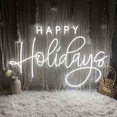 a happy holidays neon sign sitting on top of a white fluffy rug next to a vase