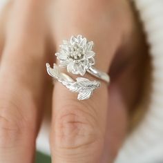 a close up of a person's hand with a flower ring on it