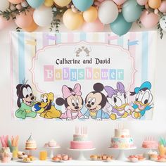 a baby shower party with mickey mouse cake and balloons in the background, including a banner